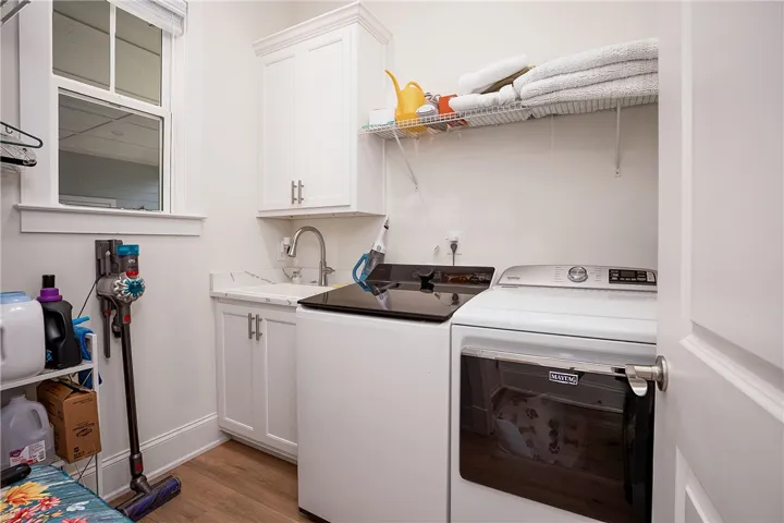 A well-appointed utility room features a sink with elegant cabinetry and practical wood flooring.