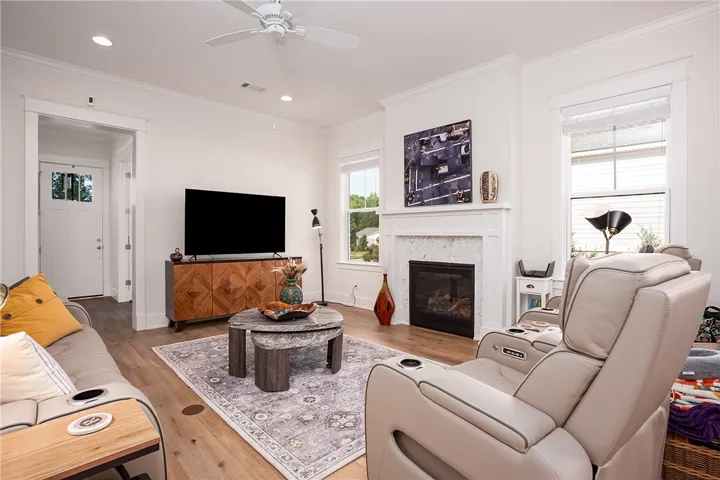 Natural light illuminates the open-concept living space, highlighting rich hardwood floors and a cozy marble fireplace.
