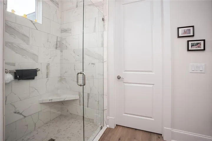 A glass-enclosed shower offers sleek modern design and a built-in bench.