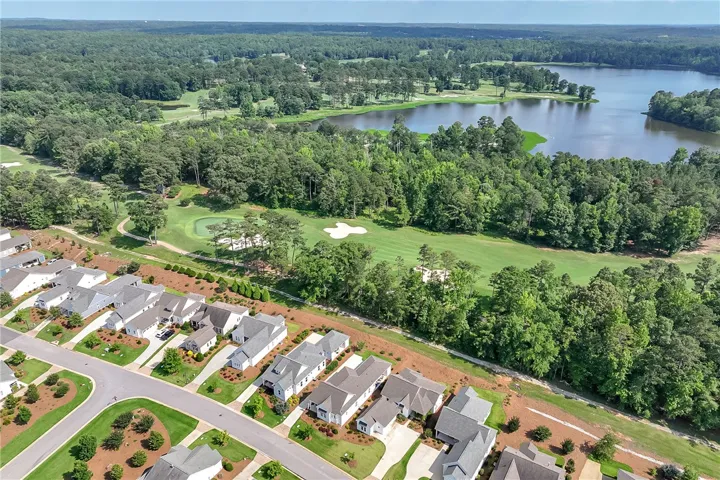An aerial perspective reveals a serene golf course bordering a shimmering lake, nestled among residential homes.