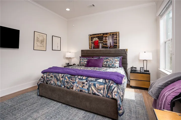Hardwood floors and tall ceilings define this well-lit bedroom space.