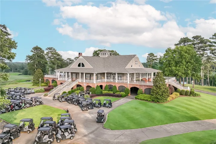 Elegant clubhouse with broad porches overlooking manicured fairways and an array of golf carts.