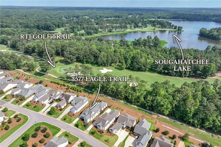 An aerial perspective reveals a serene golf course bordering a shimmering lake, nestled among residential rooftops.