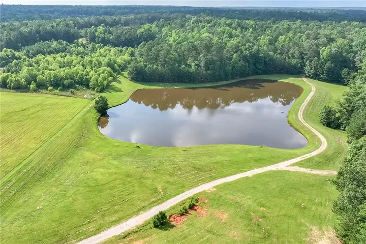 Vast green meadows and a tranquil pond offer serene rural living.