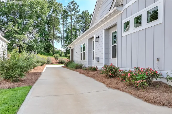 A well-maintained concrete driveway leads to this charming residence with tidy landscaping and mature trees.