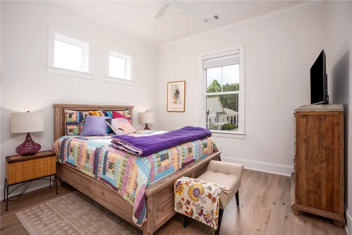 Hardwood floors and tall ceilings define this well-lit bedroom space.