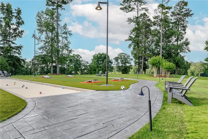 An inviting outdoor recreation area offers bocce ball, cornhole, and ample seating amidst vibrant green landscaping.