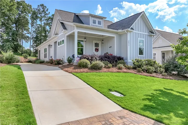 A welcoming front facade with a covered entry, lush landscaping, and a broad driveway beckons.