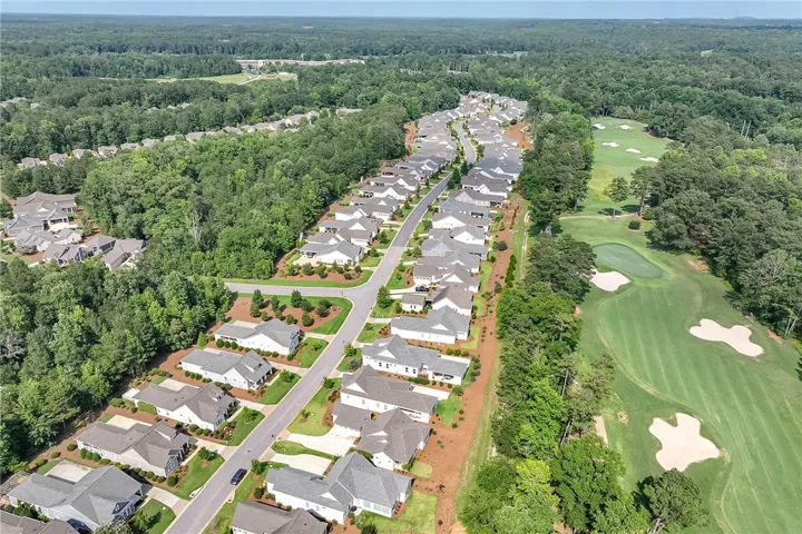 An aerial panorama reveals a residential community nestled beside a meticulously maintained golf course.