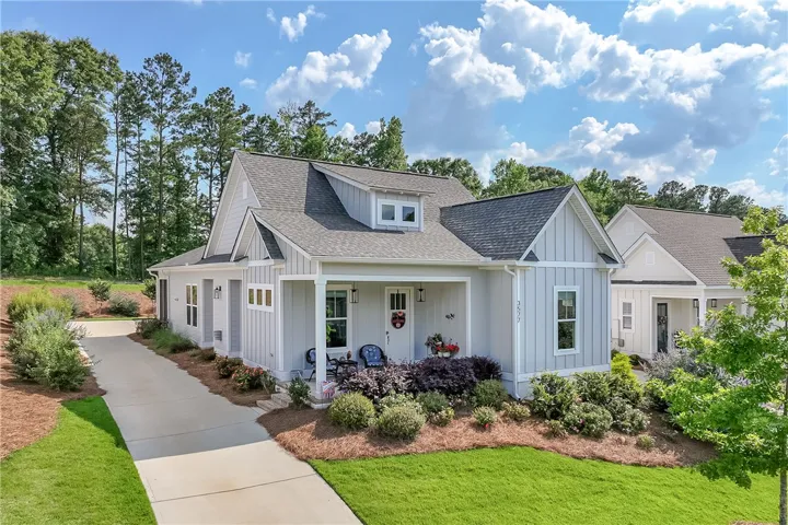 A charming cottage-style residence features a welcoming front porch and manicured landscaping.
