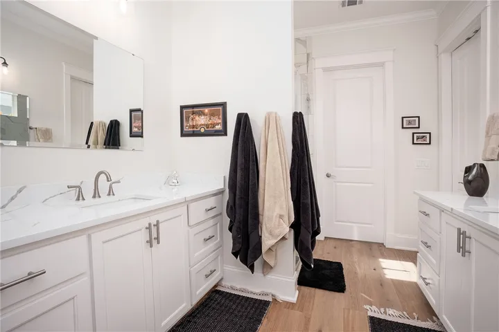 Refined bathroom with a dual vanity featuring sleek white cabinetry and marble-patterned counters.