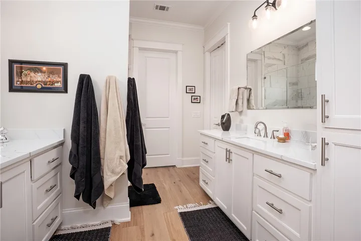 White cabinetry, light wood flooring, and modern fixtures create a serene bathroom oasis.