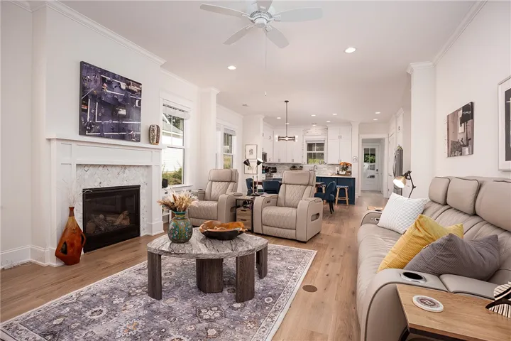 An inviting open-concept living space features a cozy fireplace, seamlessly connecting to a modern kitchen.