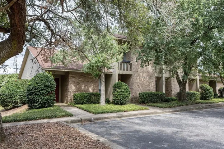 Mature trees frame this multi-story brick residence with inviting pedestrian walkways.