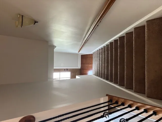 Carpeted stairs with a classic railing lead to a well-lit lower landing.