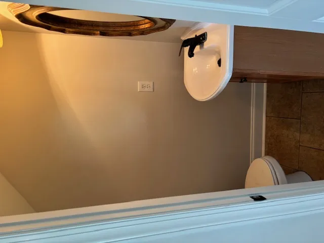 Functional full bathroom featuring a toilet and sink with warm lighting.