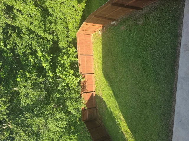 A verdant backyard with a wooden fence borders a natural treeline, offering privacy and natural beauty.