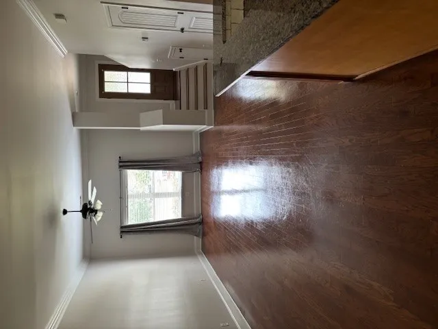 Rich hardwood floors flow through this welcoming living space, anchored by a prominent ceiling fan.