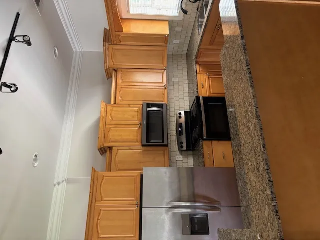 A contemporary kitchen showcasing natural wood cabinetry and resilient granite countertops.