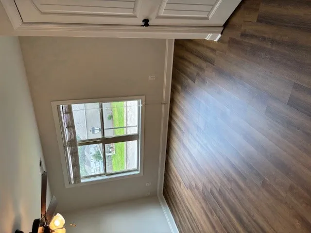 An inviting room features rich wood flooring, crisp trim, and a window with a pleasant neighborhood outlook.