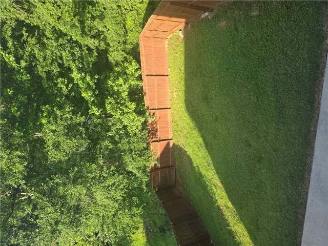 A wooden fence creates a clear boundary between verdant greenery and a manicured lawn.