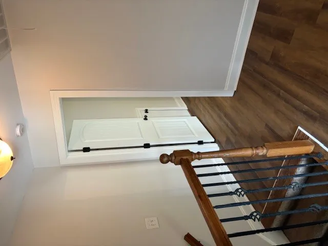 Rich hardwood flooring complements a classic staircase with wrought iron balusters.