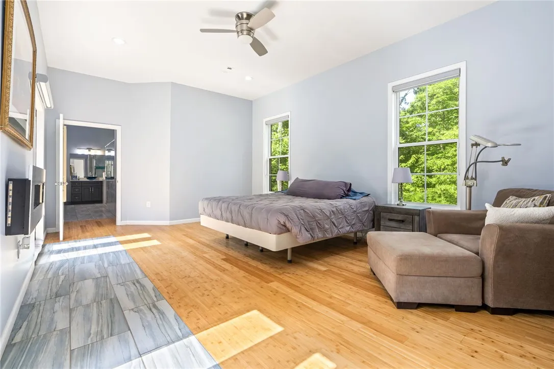 Natural light streams into this expansive primary bedroom with dual flooring and private bath access.