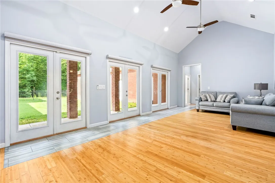 Natural light pours into this living space through multiple glass French doors, highlighting the vaulted ceilings.