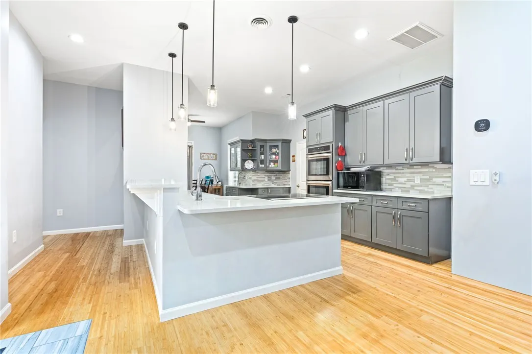 A streamlined kitchen showcasing hardwood floors, built-in appliances, and a convenient island with breakfast bar.