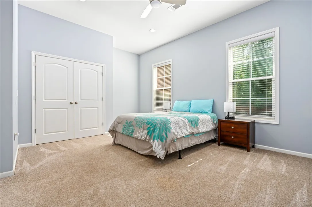 A tranquil primary bedroom with plush carpet and large windows for ample natural illumination.