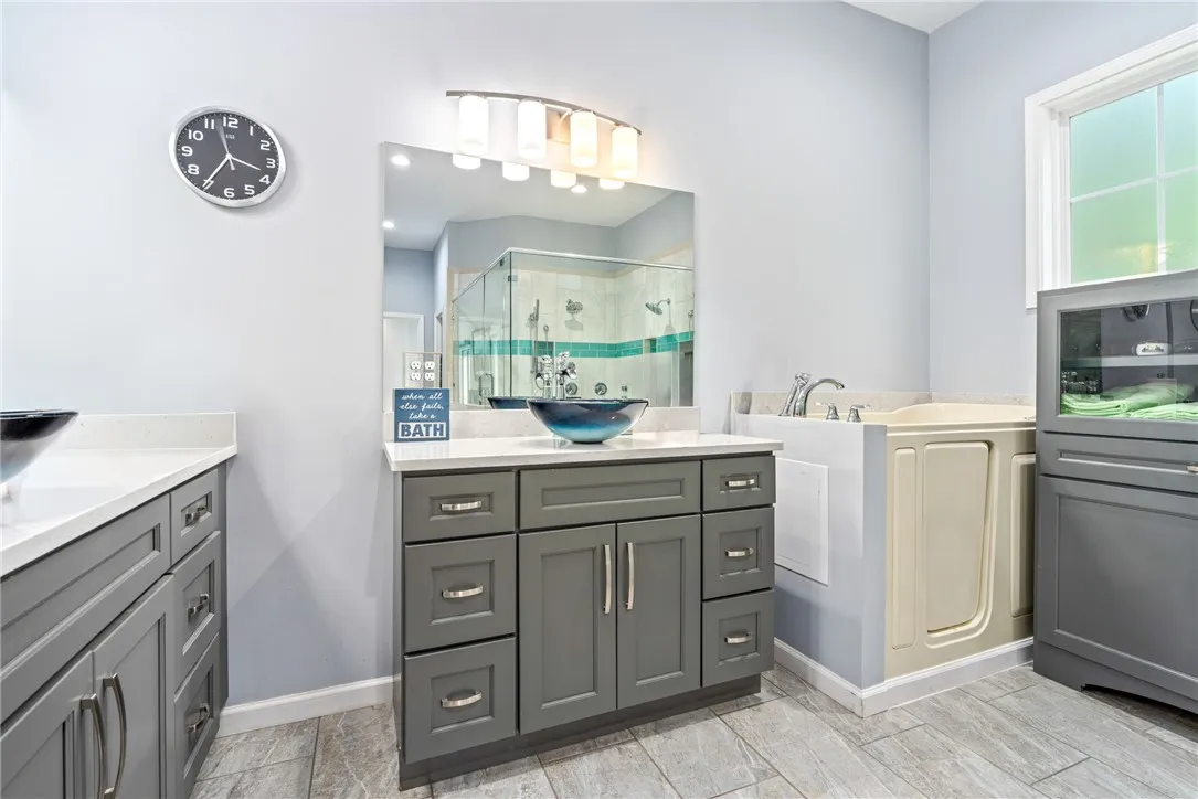 Elegant gray vanity and walk-in tub offer a serene bathing experience.