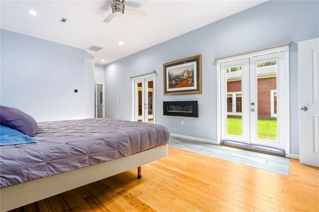 Relaxing primary bedroom with direct outdoor access and an elegant wall-mounted fireplace.
