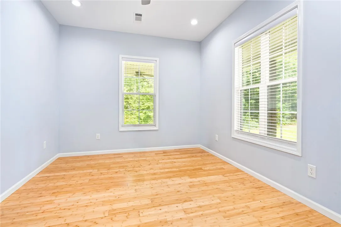 Blinds adorn dual windows, complementing the warm hardwood flooring in this versatile room.