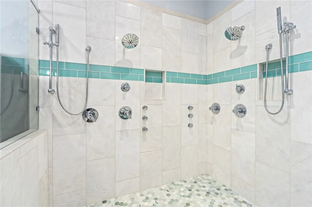 Double rainfall showerheads and body jets define this generously tiled, walk-in shower.