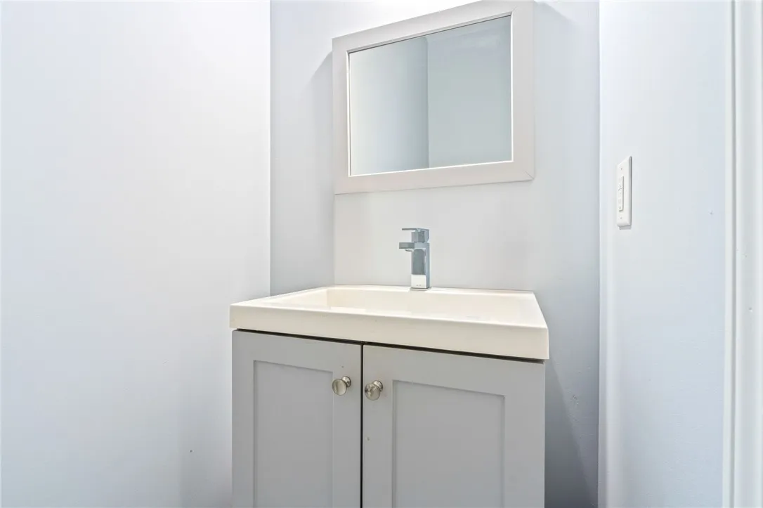 A sleek vanity with a modern faucet and clean mirror defines this compact bathroom space.