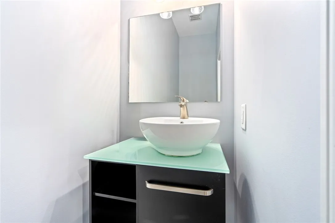 A modern vanity with a vessel sink and glass counter creates a striking bathroom aesthetic.