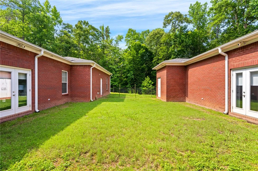 A verdant backyard retreat offering privacy with brick structures and mature trees.