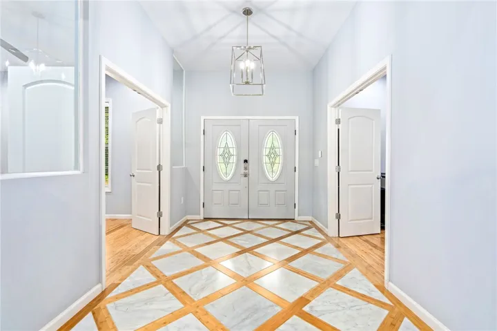 A grand entrance welcomes all with a distinctive inlaid tile and hardwood flooring pattern.