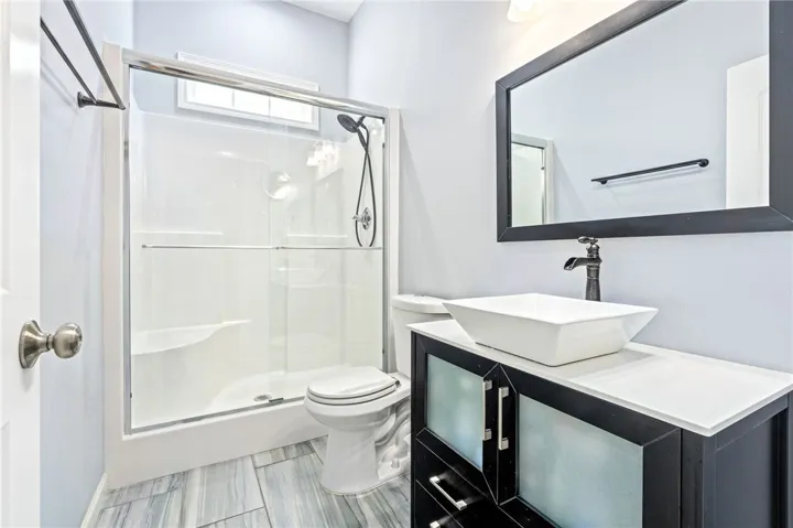 A well-appointed bathroom features a modern vanity with a vessel sink and a spacious glass-enclosed shower.