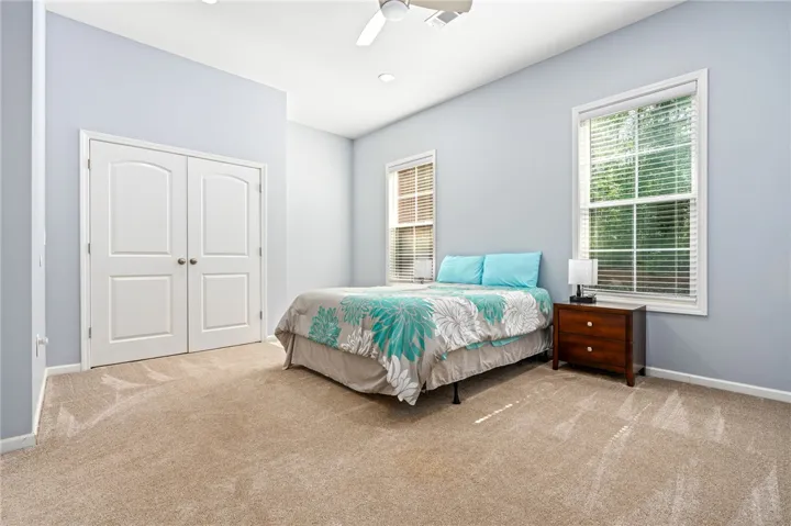 A tranquil primary bedroom with plush carpet and large windows for ample natural illumination.