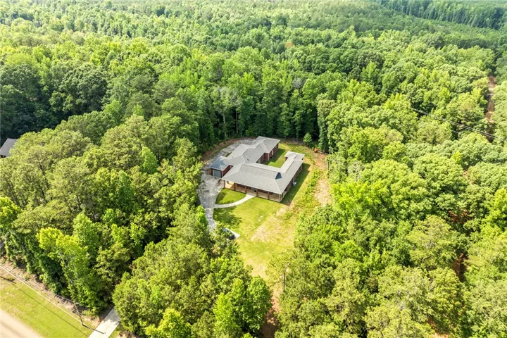 An aerial perspective reveals a secluded residence nestled within a verdant, expansive wooded property.