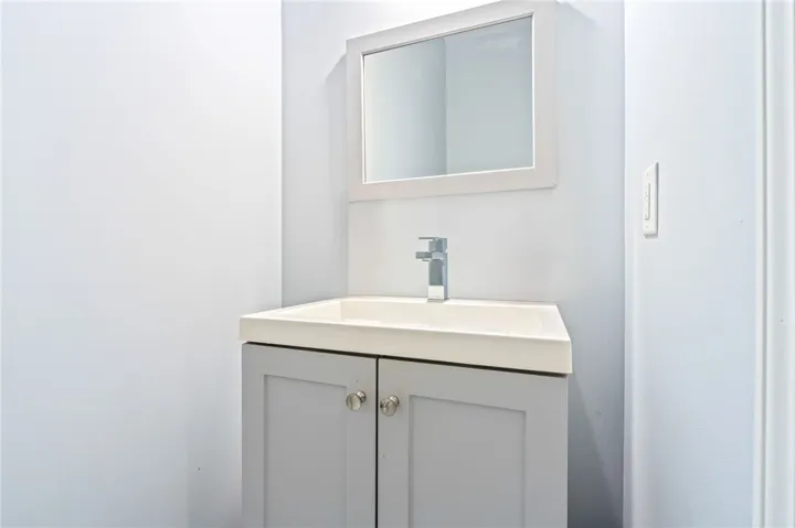 A sleek vanity with a modern faucet and clean mirror defines this compact bathroom space.