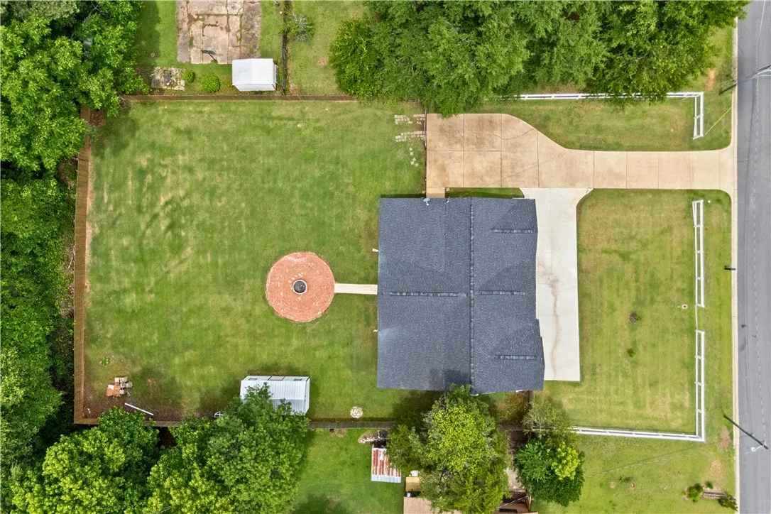 An aerial perspective reveals a well-maintained property with a prominent circular brick patio and a spacious, verdant yard.