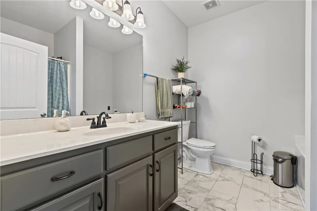 Marble-look tile flooring grounds this full bathroom with a spacious vanity and ample storage.