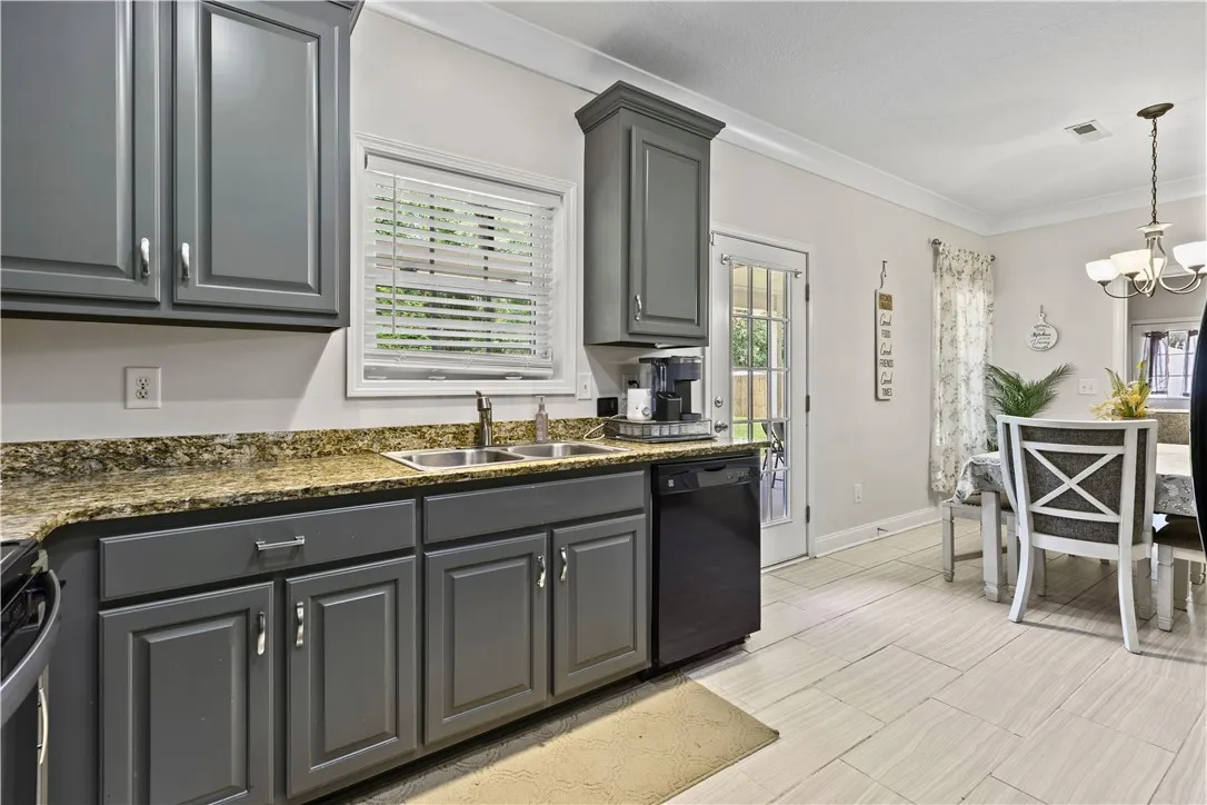 Granite counters and light wood-look tile flooring elevate this functional kitchen with direct outdoor access.