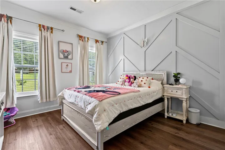 Natural light streams into this bedroom with its distinctive accent wall and rich LVP flooring.