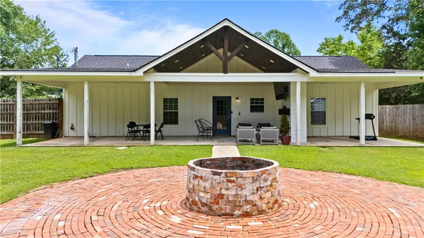 A spacious backyard patio, brick fire pit, and ample green space define outdoor living at this residence.