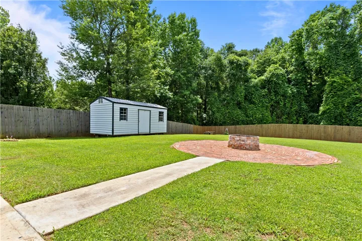 A well-maintained yard offers a shed and a circular brick patio with a fire pit for outdoor enjoyment.