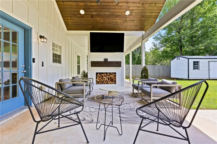 An inviting covered patio featuring a built-in fireplace and serene backyard views.