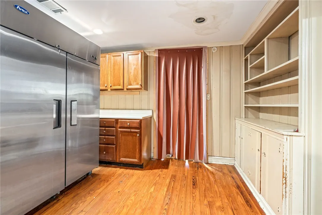 A commercial-grade refrigerator anchors this kitchen space, complemented by honey-toned cabinetry and built-in shelving.